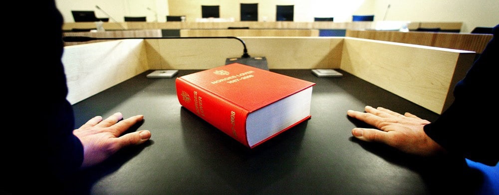 En person i en rettsak med lovboka foran seg. Bilde.